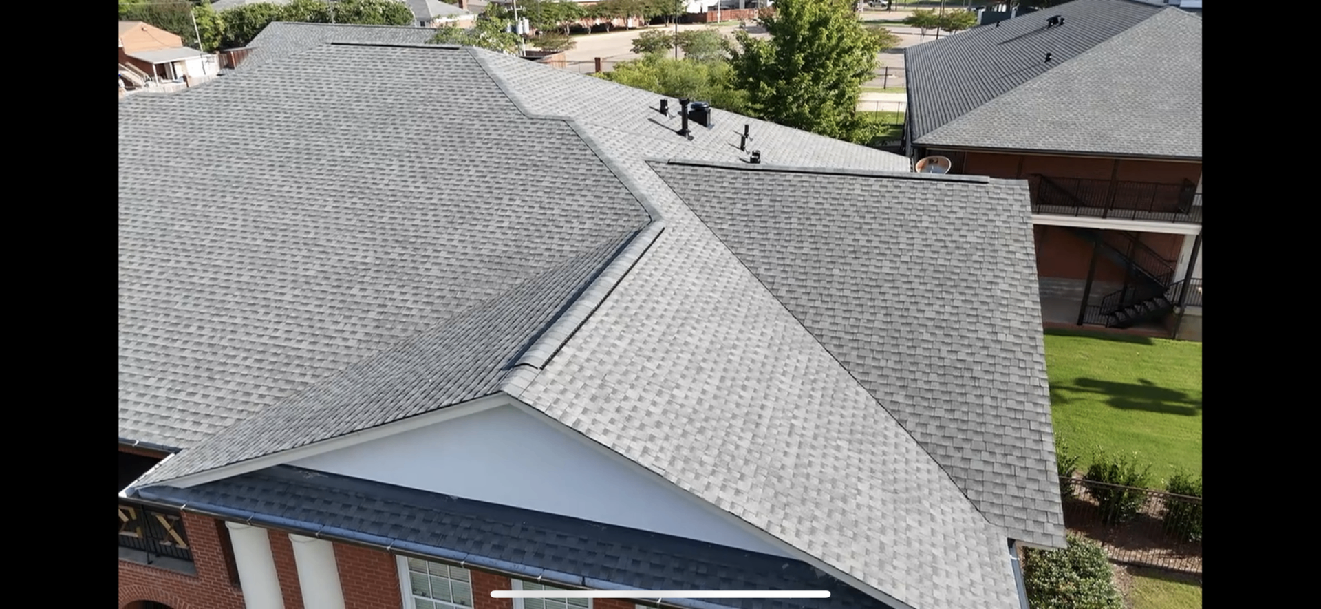 Aerial view of completed light gray architectural shingle roof on fraternity house in Starkville MS