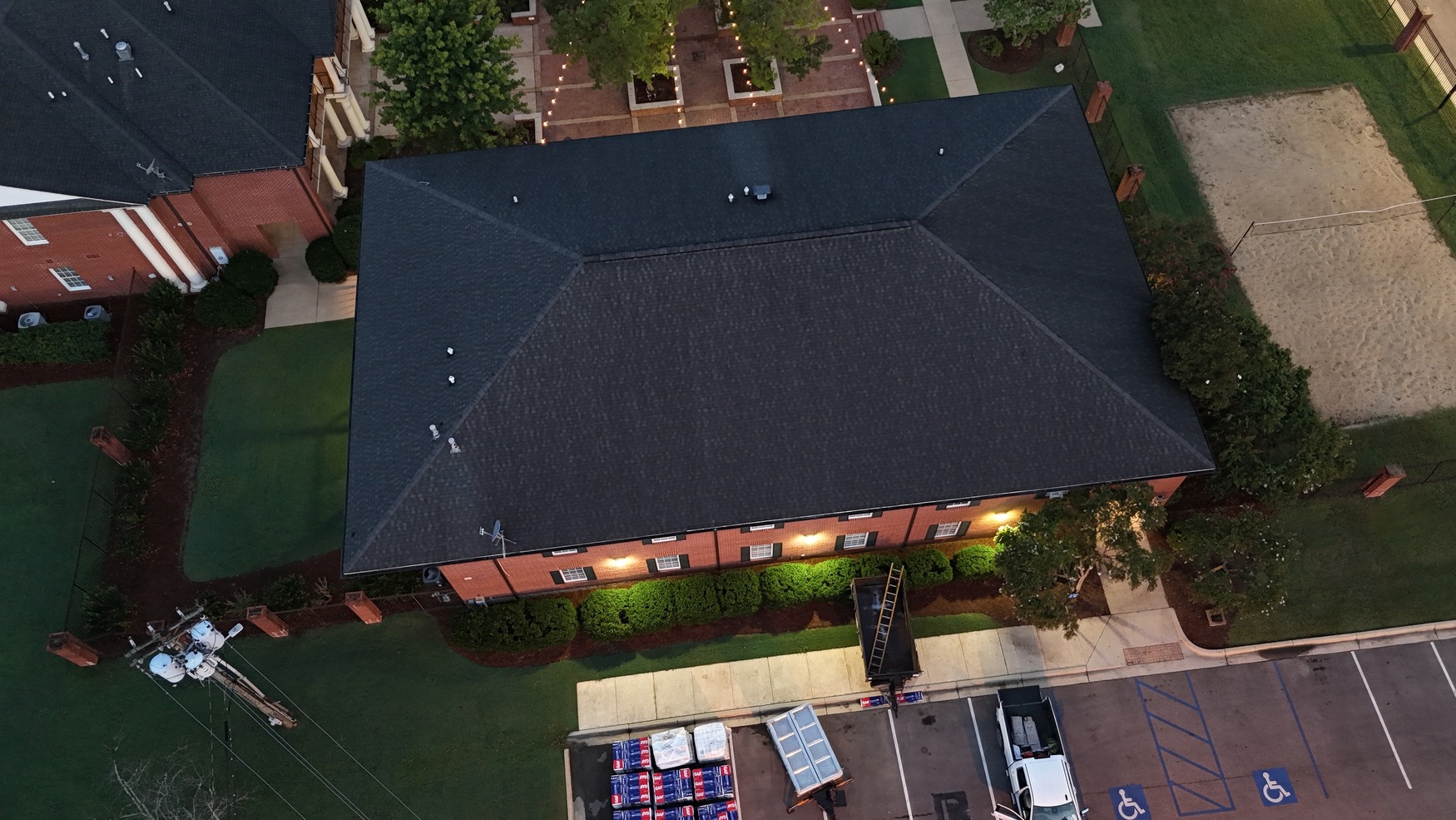 Aerial drone shot of completed dark shingle roof on large commercial brick building in Starkville MS